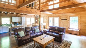 A spacious living area with leather sofas, a wooden coffee table, and a kitchen in the background. - Hillside Haven | Luxe Hot Tub | Cornhole | Jenga (Whitwell)
