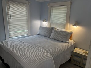 A bedroom with a bed, two bedside lamps, and a nightstand.
