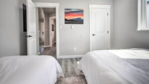 Een slaapkamer met twee bedden, een deur en een schilderij aan de muur.