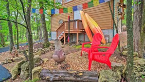 A wooden cabin with a deck, surrounded by trees and rocks. - Bright Lakeside Studio - Hike, Fish, and Bike! (Golden)