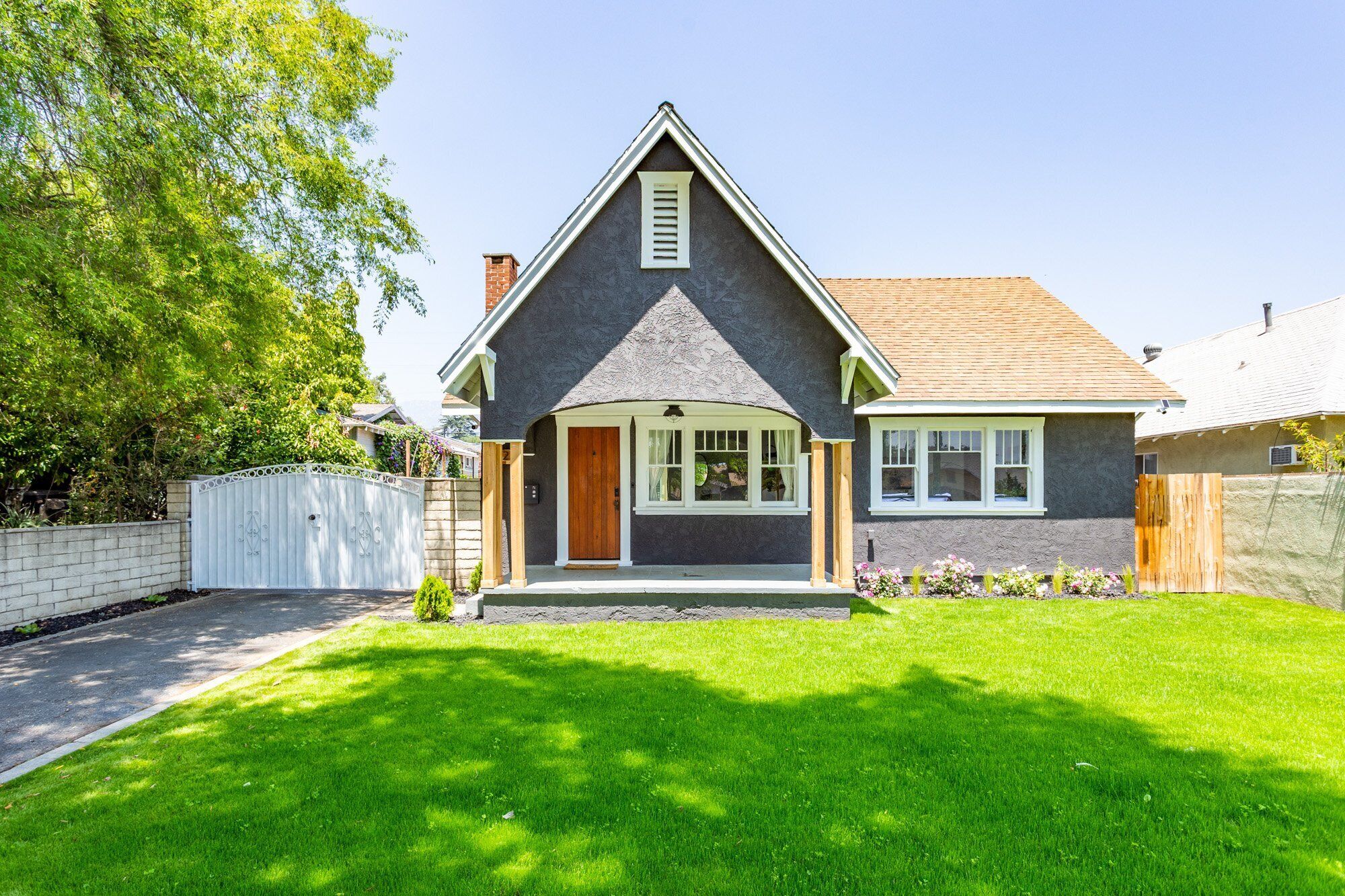 Een tweelaags huis met een puntige dakkapel, een veranda en een verzorgd gazon.