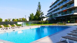 Una piscina con sdraio e un edificio moderno sullo sfondo.