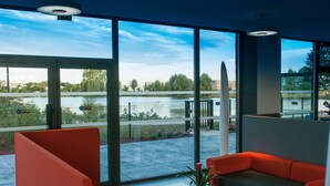 Un interno moderno con ampie finestre che si affacciano su uno specchio d'acqua e del verde.
