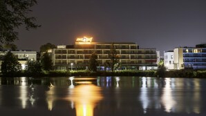 Ein Hotel mit einem 'mergolf'-Schild, das sich im Wasser spiegelt, umgeben von weiteren Gebäuden.
