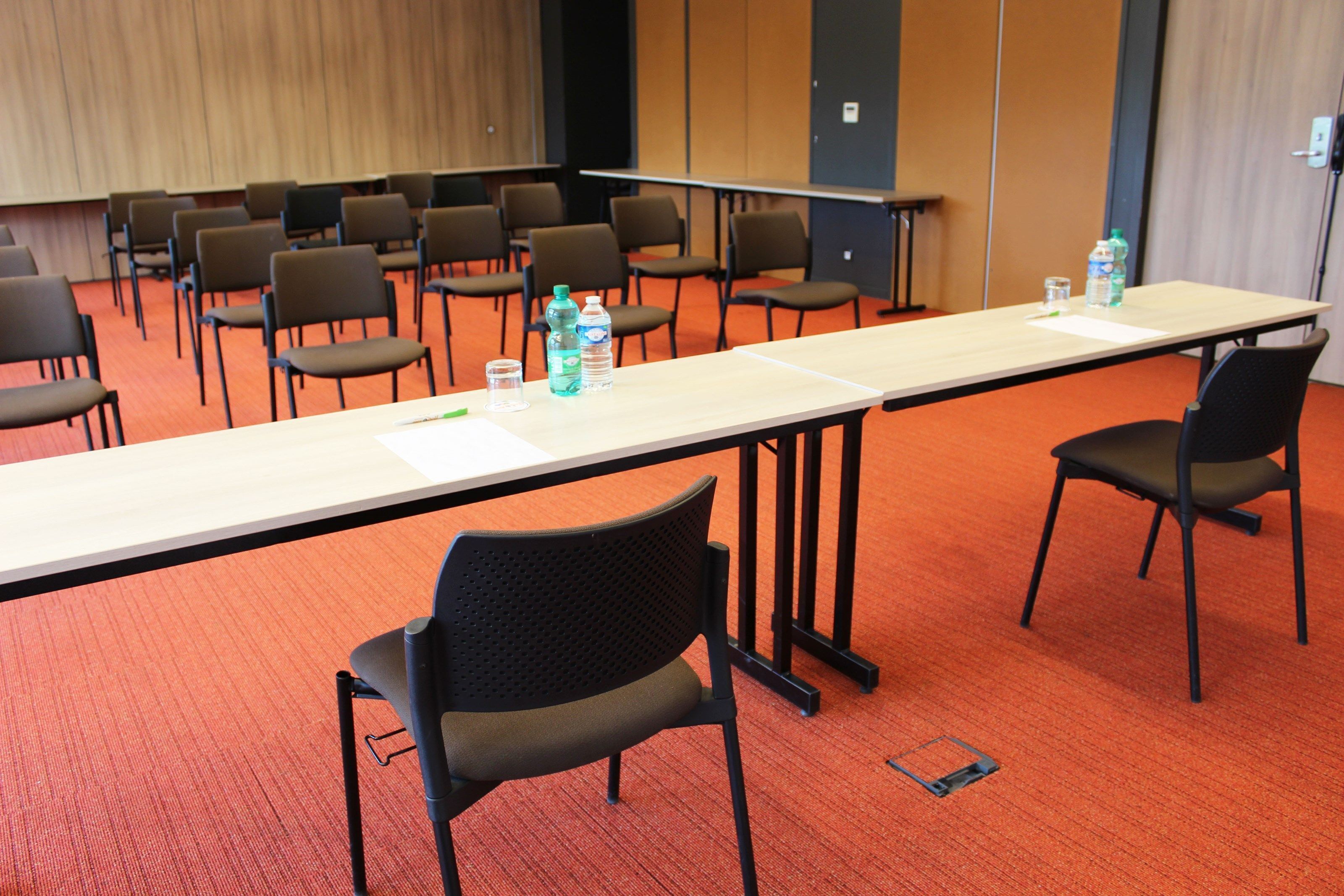 A conference room with a long table, multiple chairs, and water bottles on the table.