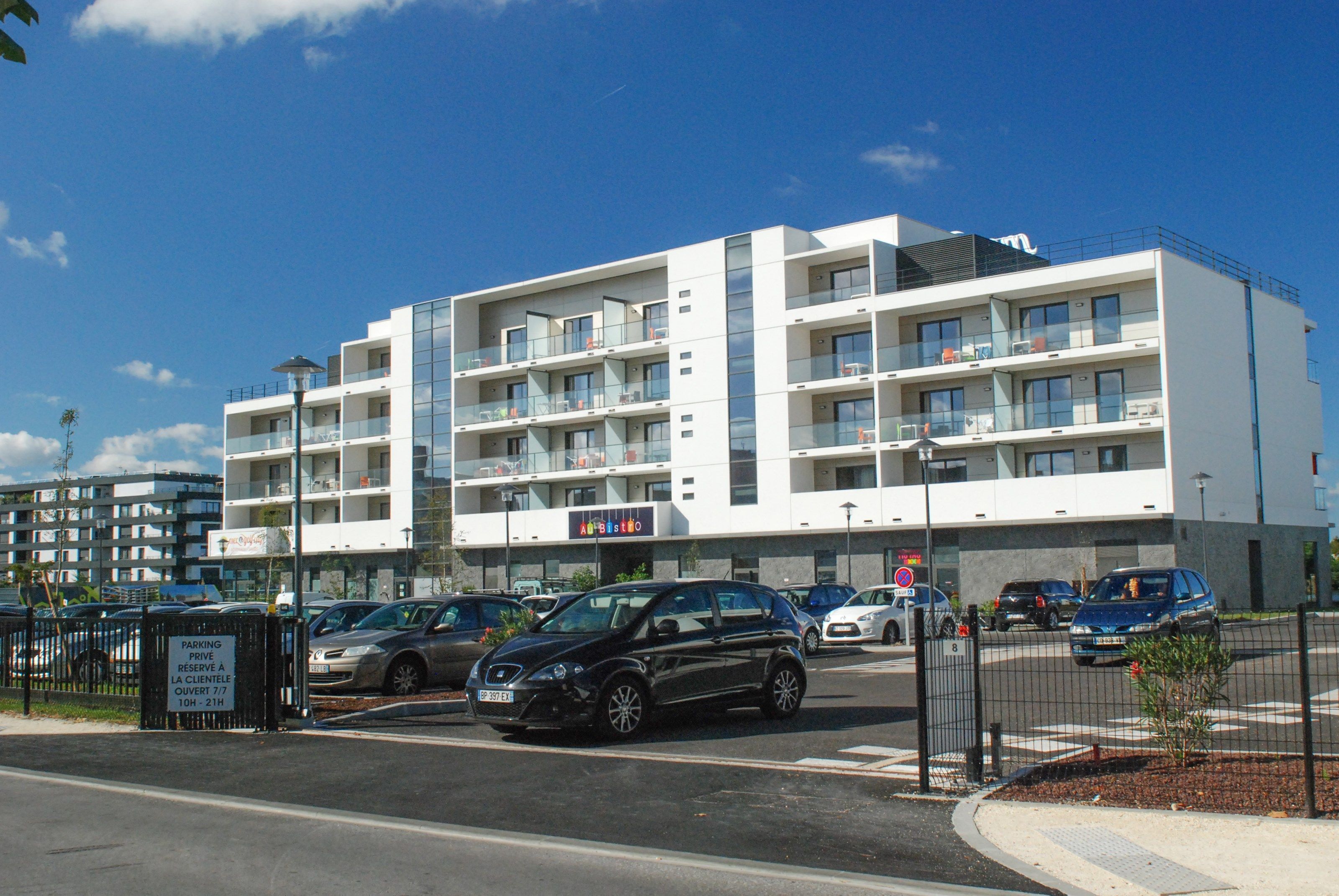 Un hôtel à plusieurs étages doté de balcons, d’un espace de stationnement et d’un panneau indiquant la présence d’un parking privé.