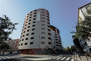 A multi-story hotel with a curved facade, multiple balconies, and a central entrance. - Studio Confortable + Kitchenette | Wi-Fi Gratuit (Perpignan)
