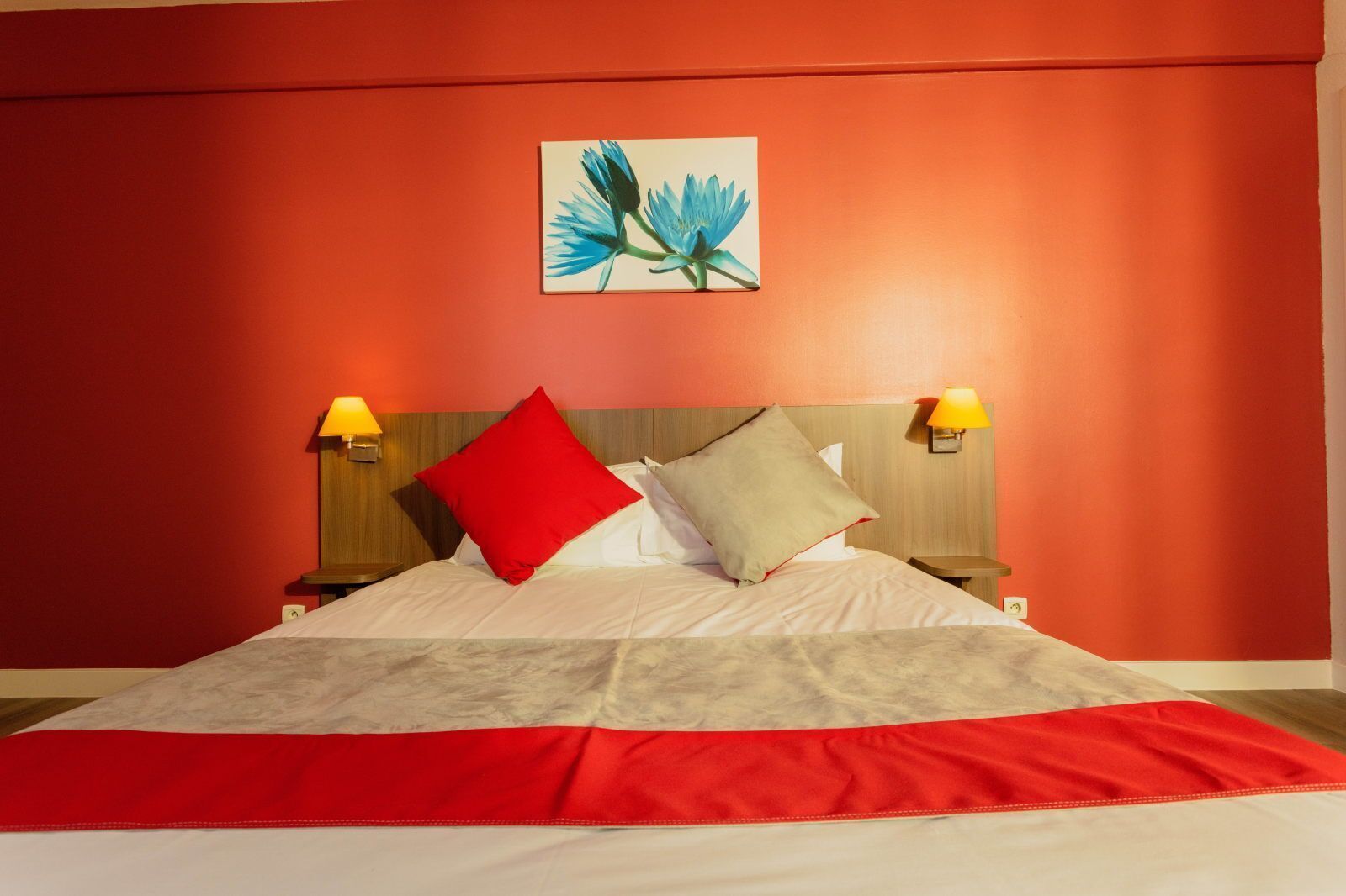 A hotel room with a large bed, two bedside lamps, and a painting on the wall.