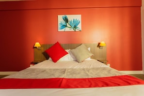 A hotel room with a large bed, two bedside lamps, and a painting on the wall.