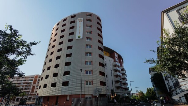 A multi-story hotel with a curved facade, multiple balconies, and a central entrance.
