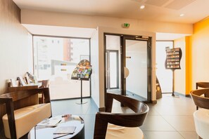 Un hall d’hôtel avec des sièges, un comptoir d’accueil, une entrée avec une porte vitrée et un présentoir à magazines.