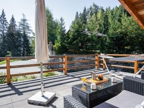 Une terrasse dotée de mobilier d’extérieur, d’un hamac et d’un mur en pierre.