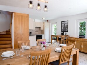 Una cocina moderna con armarios de madera, una mesa de comedor para cuatro personas e iluminación colgante.