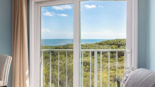 A room with a large window offering a view of a coastal landscape.
