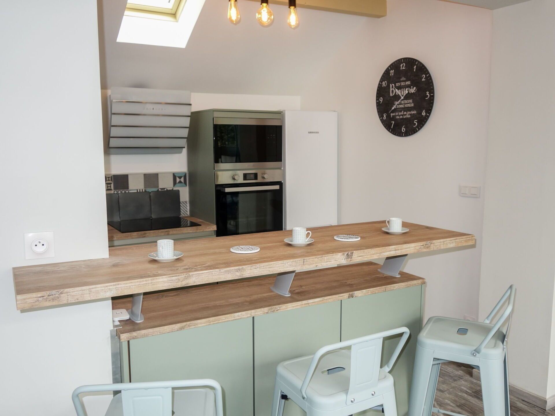 A modern kitchen with a wooden countertop, two white chairs, and a black clock on the wall.
