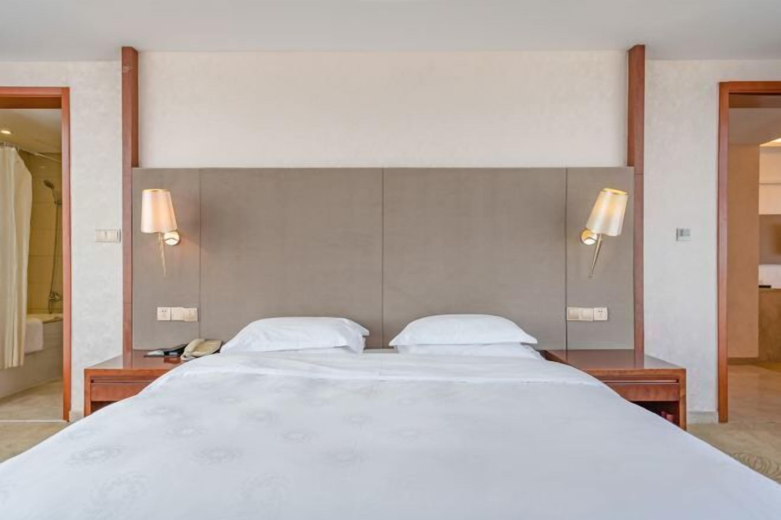 Een hotelkamer met een groot bed, twee nachtkastjes en twee wandlampen.