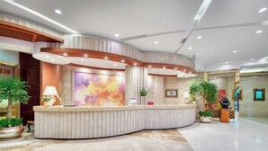 Un espace d’accueil moderne, doté d’un comptoir d’accueil incurvé, d’un éclairage encastré et d’un grand tableau abstrait accroché au mur.