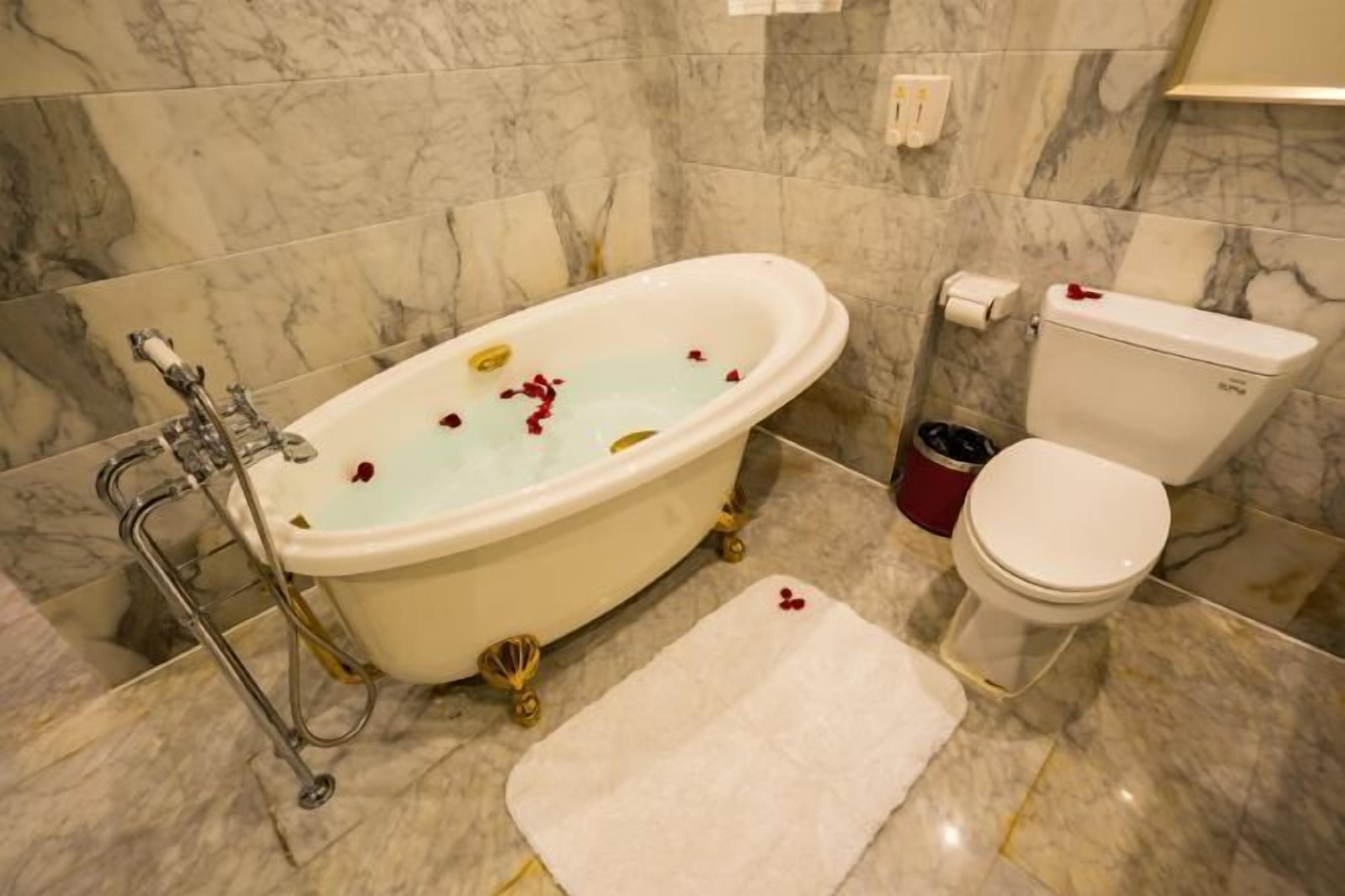 A bathroom with a bathtub, toilet, and marble tiles.