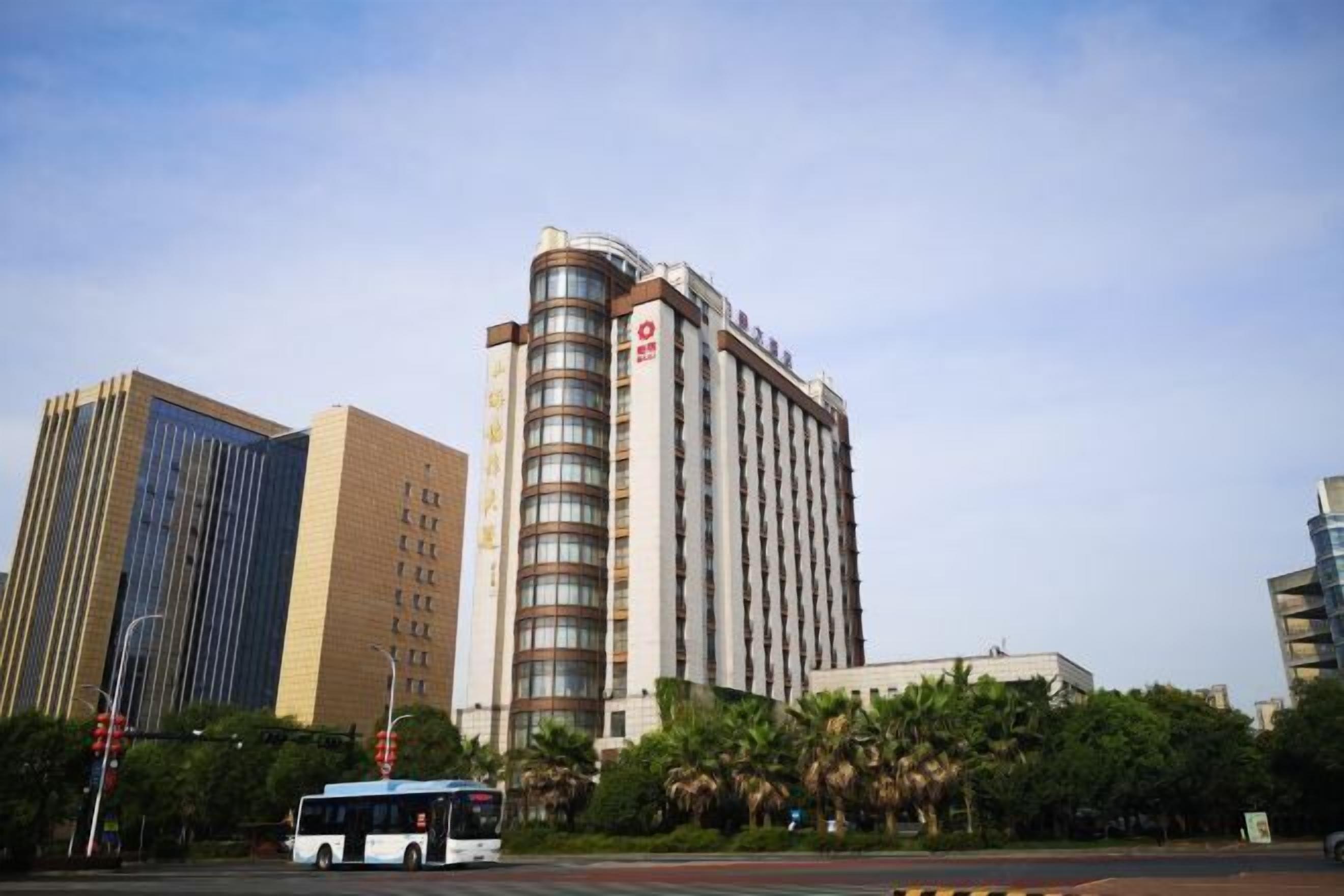 Un hotel de varios pisos con un diseño moderno, que destaca por una fachada curva pronunciada y una serie de balcones.