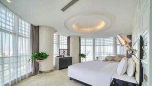 Une chambre spacieuse avec un grand lit, un téléviseur à écran plat et une plante en pot.
