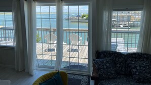 A room with a view of a dock and water, a wooden deck outside, and a sofa with a starfish pattern. - Waterfront South End Serenity! Bring your boat and your pup, leave the linens!
 (Holly Ridge)
