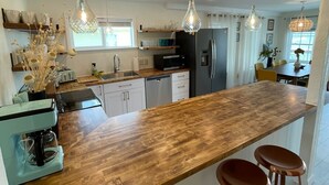 A modern kitchen with a wooden countertop, stainless steel appliances, and pendant lighting. - Waterfront South End Serenity! Bring your boat and your pup, leave the linens!
 (Holly Ridge)
