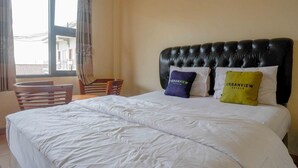 A hotel room with a large bed, two pillows with "URBANVIEW HOTELS" branding, a wooden chair, and a window with curtains. - OYO 4014 Hotel Bergas Indah (Bergas Kidul)