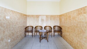 A room with beige tiled walls and floor, a wooden table with chairs, and a ceiling with a decorative design. - OYO 4014 Hotel Bergas Indah (Bergas Kidul)
