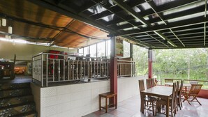 A covered outdoor seating area with a tiled floor, a staircase, and a railing. - OYO 4014 Hotel Bergas Indah (Bergas Kidul)