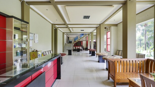 A hotel lobby with a reception desk, seating area, and a staircase leading to upper floors. - OYO 4014 Hotel Bergas Indah (Bergas Kidul)