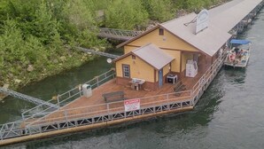 Une péniche amarrée, dotée d’une petite terrasse, d’une table à manger et d’un panneau d’avertissement indiquant un danger.