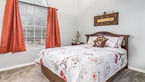 Une chambre à coucher avec un lit, une fenêtre avec des rideaux, une table de chevet avec une lampe et un élément décoratif mural.