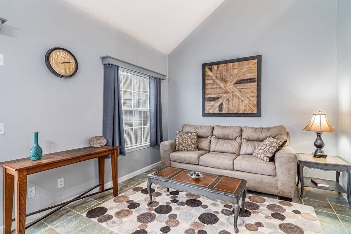 A living room with a sofa, coffee table, and a painting on the wall.