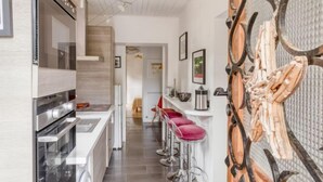 A modern kitchen with stainless steel appliances, a central island with bar stools, and a decorative wooden panel on the wall. - Villa Giroflé by Interhome (Arcachon)