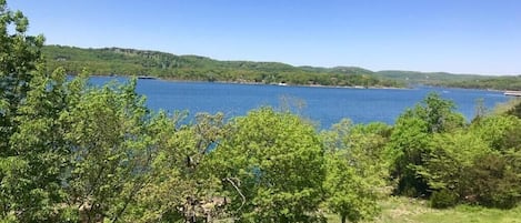 A view of a lake with trees in the foreground and hills in the background.