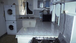 A kitchen with a gas stove, a washing machine, and a sink.