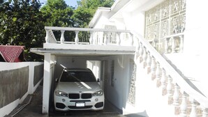 A white building with a covered car entrance and a staircase.