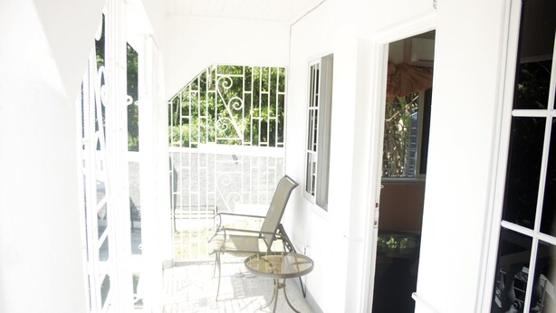 A bright, sunlit room with a glass door leading outside, a small round table, and a chair.