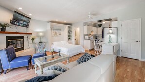 Un salon moderne avec un canapé, un fauteuil bleu, une table basse et un téléviseur fixé au mur.