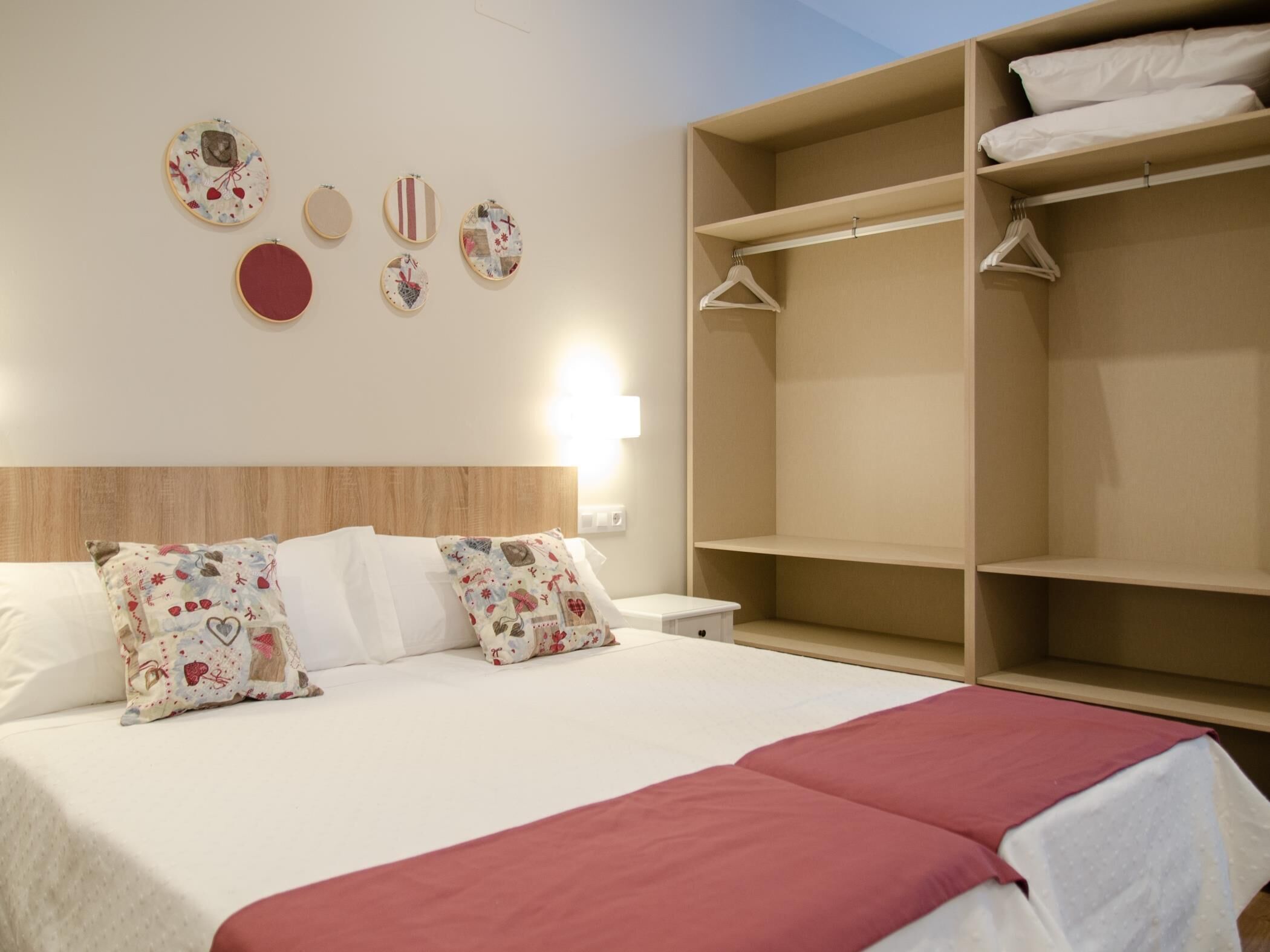A hotel room with a bed, a wardrobe, and a wall with decorative items.