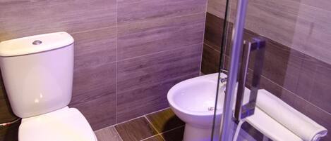 A modern bathroom with a toilet, bidet, and glass shower enclosure.