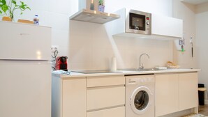 Una cocina moderna con lavadora integrada, microondas y refrigerador de acero inoxidable.
