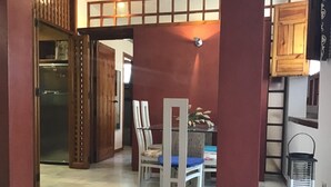 A dining area with a table and chairs, a refrigerator in the background, and a wooden partition.