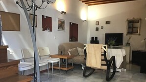 A living room with a sofa, chairs, a small table, a TV, and a staircase.