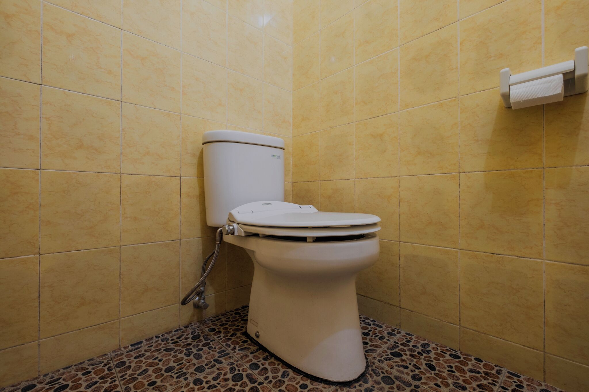 A toilet in a bathroom with tiled walls and a patterned floor.