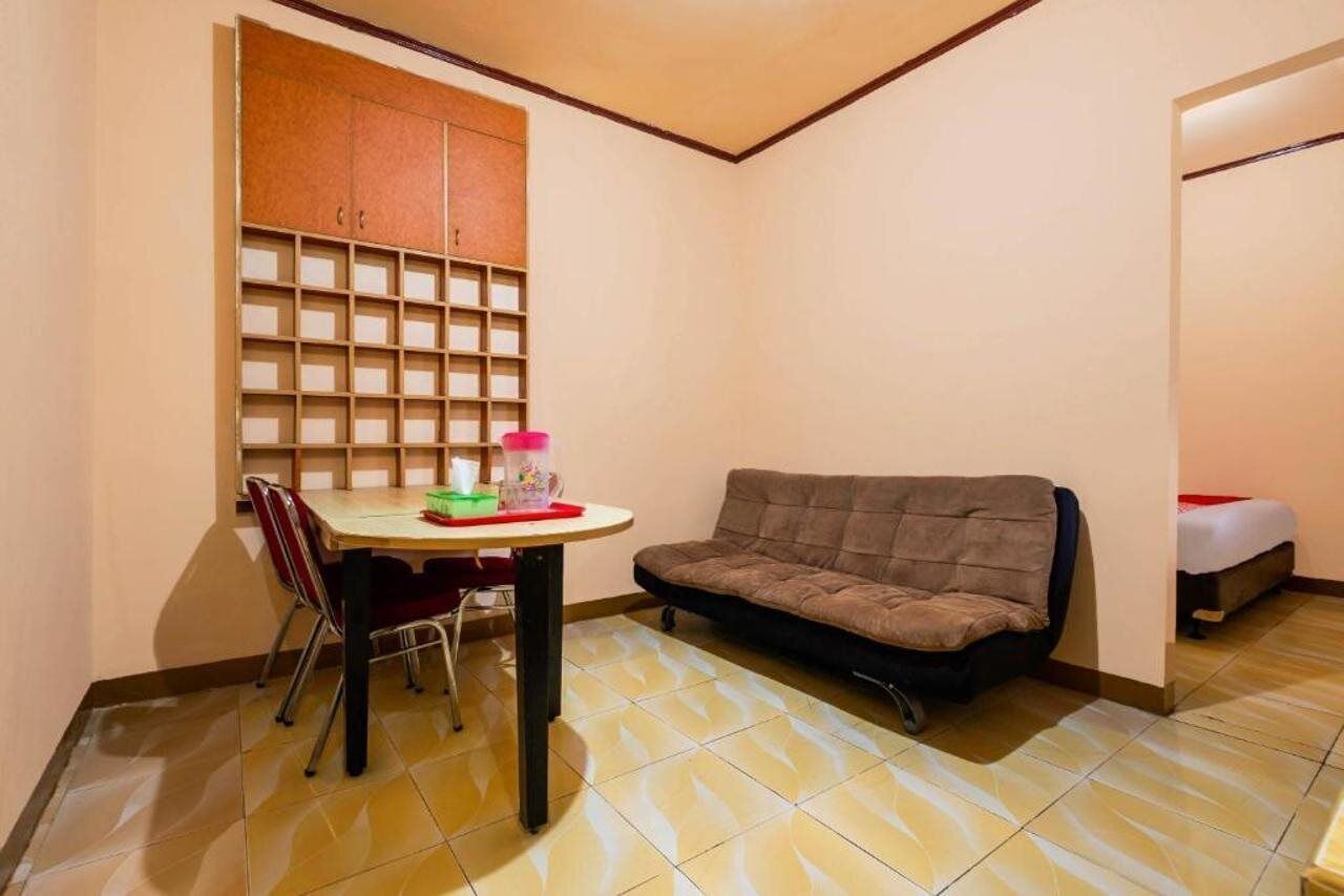 Une petite pièce comprenant une table à manger, des chaises, un canapé, un meuble avec des compartiments de rangement et un lit.