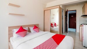 Een hotelkamer met een bed, een kledingkast en een kitchenette.