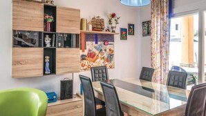 A dining area with a glass-top table, black chairs, and a wooden cabinet with shelves. - Nice house with private pool and barbacue (Vidreres)