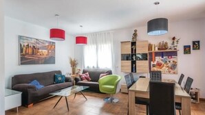 A modern living room with a sofa, a green chair, a glass coffee table, and a dining table with chairs. - Nice house with private pool and barbacue (Vidreres)