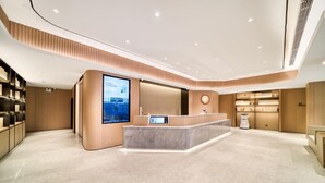 A modern reception area with a curved reception desk, a large digital display, and a clock on the wall. - JI Hotel Shanghai Chuansha Branch (Shanghai)